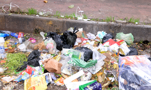 நடைபாதையோரம் குவிந்து கிடக்கும் குப்பை