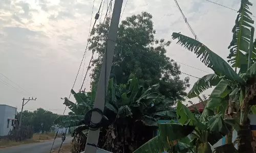 சாய்ந்த நிலையில் மின்கம்பம்