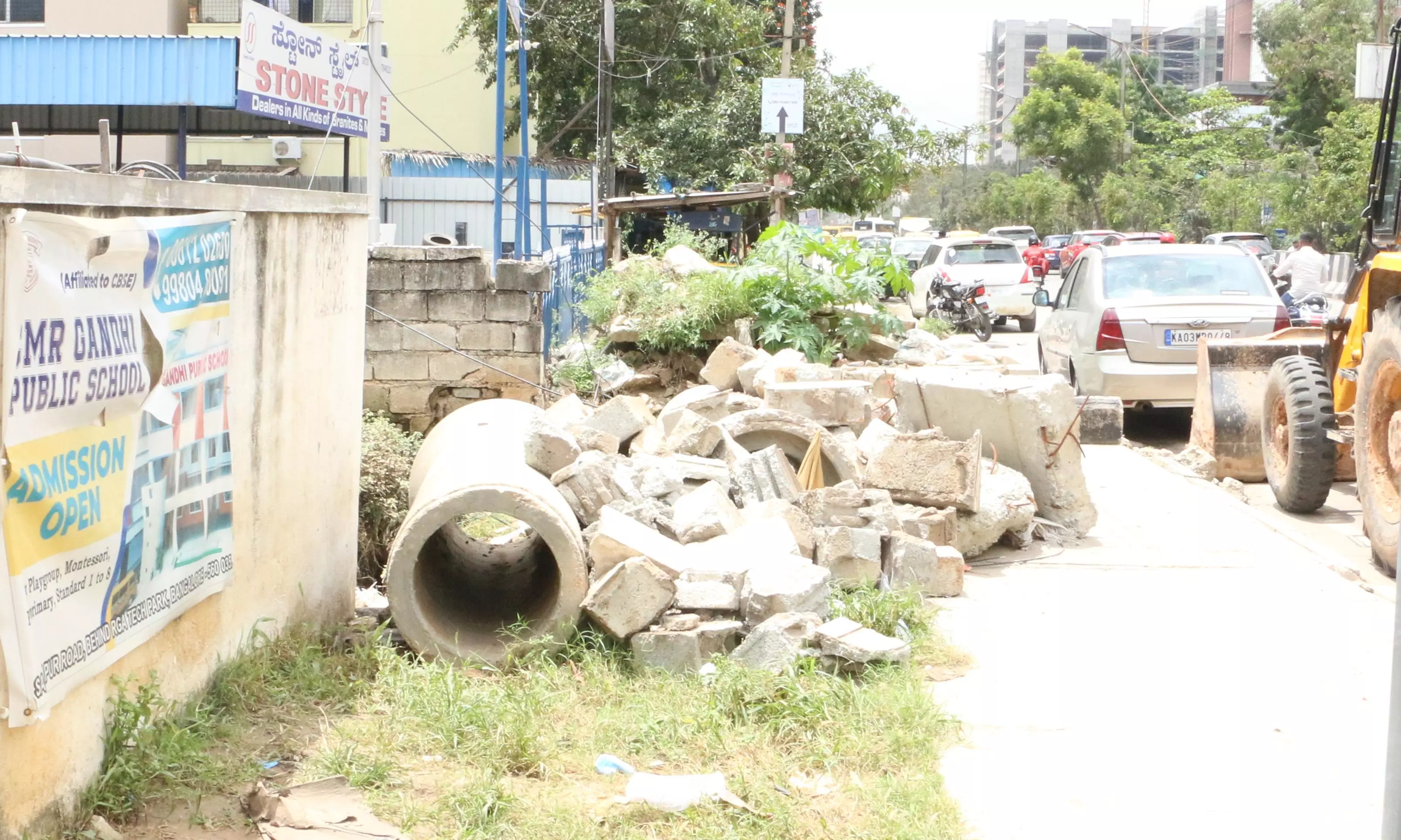 நடைபாதையில் கிடக்கும் சிமெண்டு குழாய்கள்