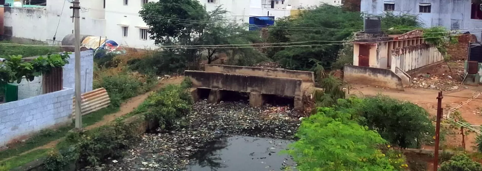 குளத்தின் ஓடையில் குவிந்த குப்பைகள்