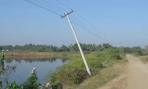 சாய்ந்த நிலையில் மின்கம்பம்