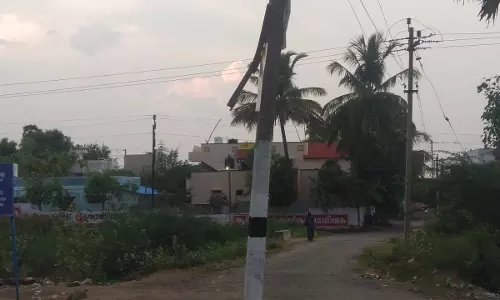 சாலையின் நடுவே உள்ள மின்கம்பம்