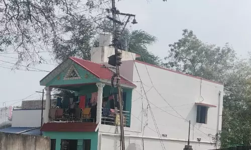 சாலையின் நடுவில் மின்கம்பம்
