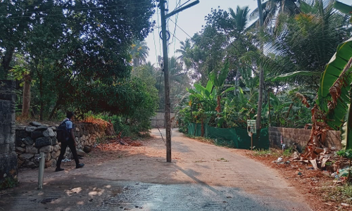 சாலை நடுவே நிற்கும் மின்கம்பம்